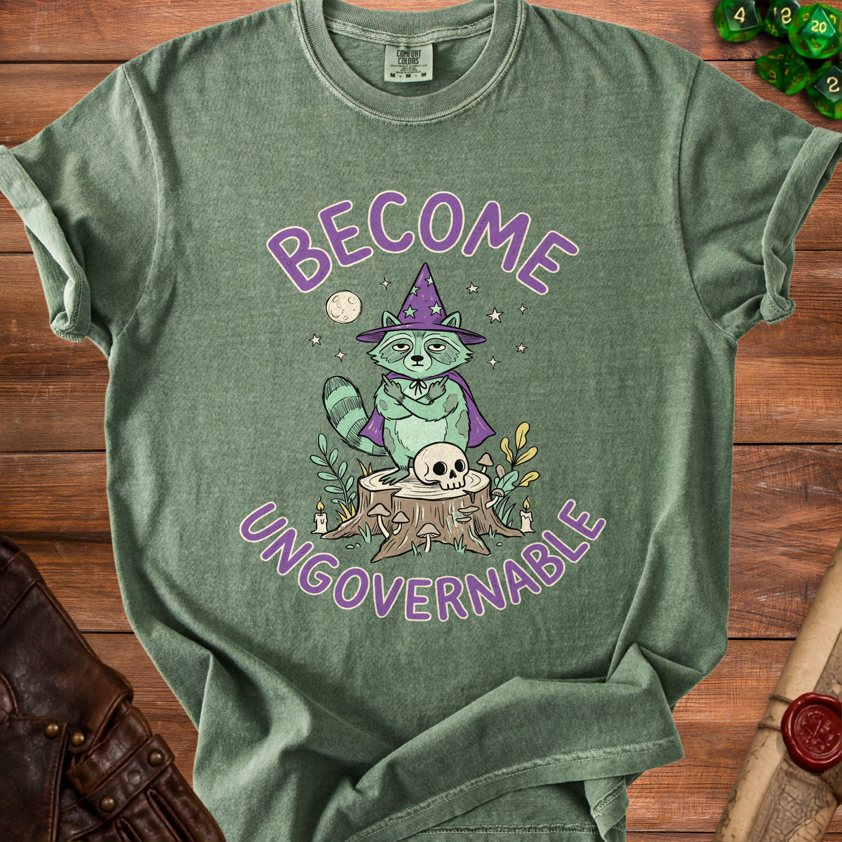 Green t-shirt with raccoon wizard graphic and text "BECOME UNGOVERNABLE"
