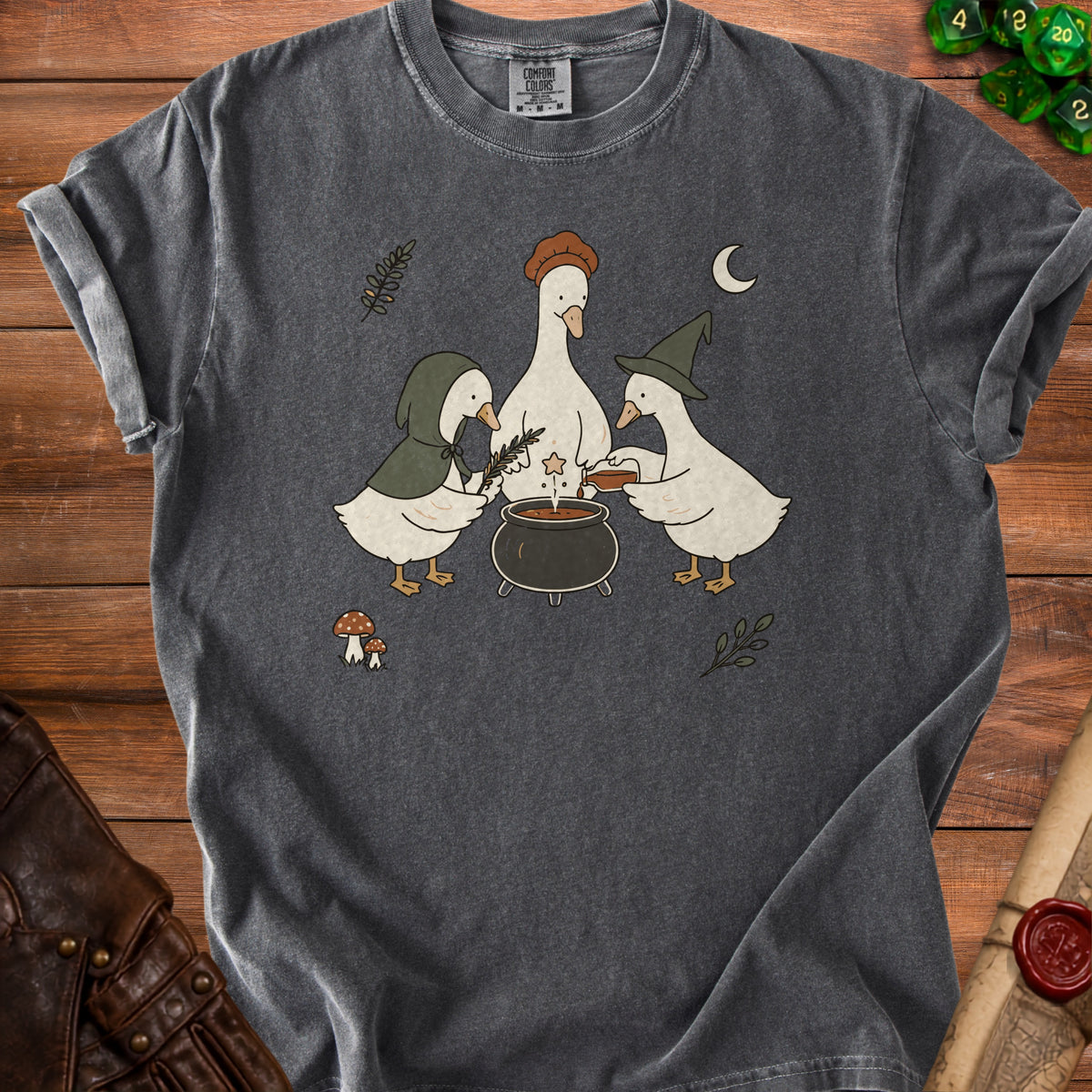 Gray t-shirt featuring three ducks around a cauldron with whimsical woodland elements.