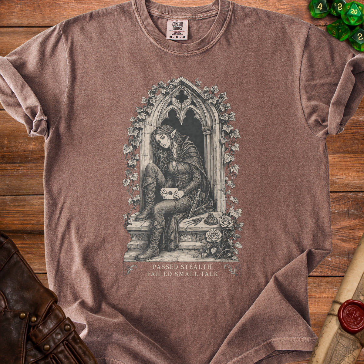 Brown t-shirt with a gothic illustration of an elf holding a letter and text "PASSED STEALTH FAILED SMALL TALK".