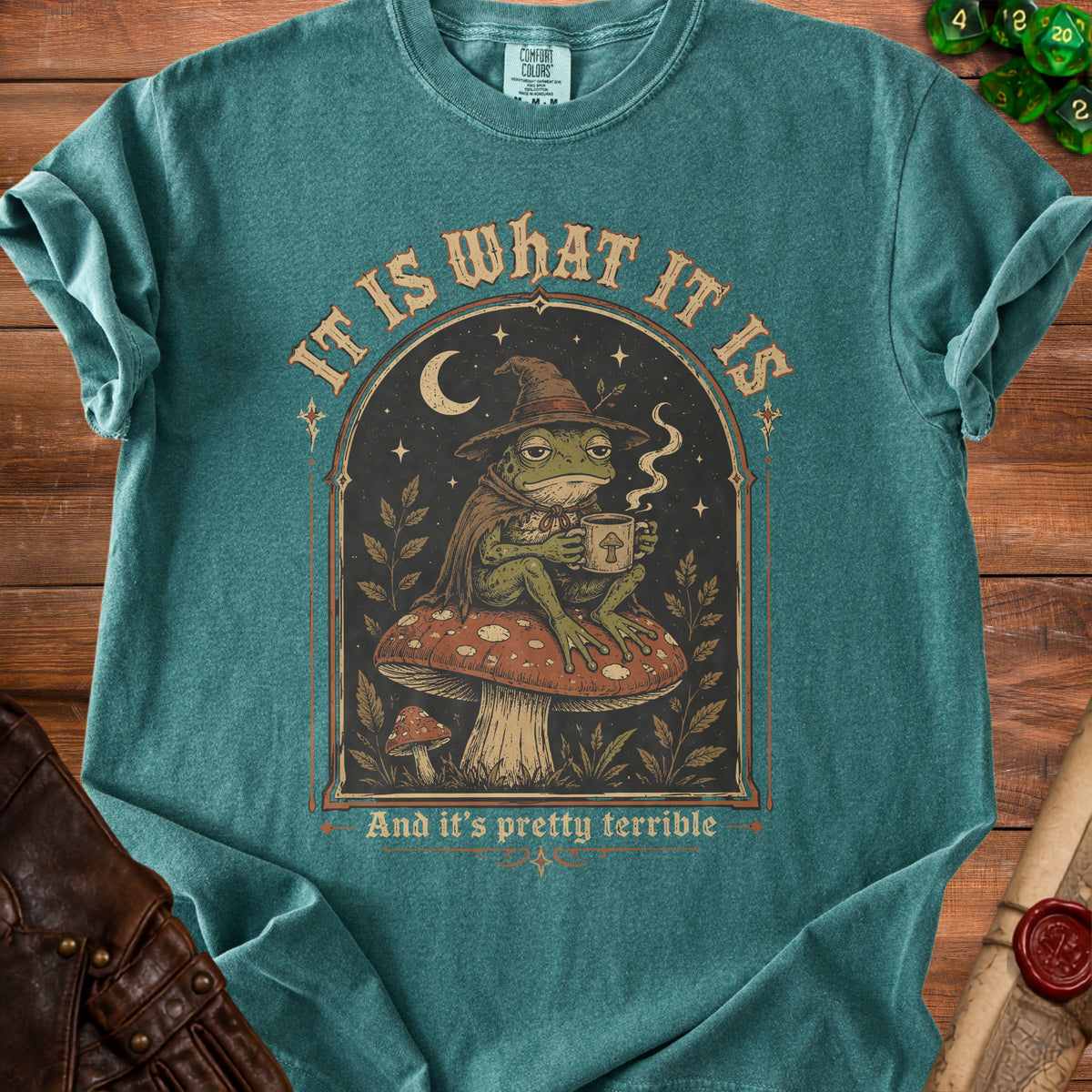 T-shirt with frog in witch hat on mushroom, text "It is what it is".