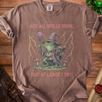 Brown t-shirt with wizard frog graphic and text "NOT ALL SPELLS WORK BUT AT LEAST I TRY".