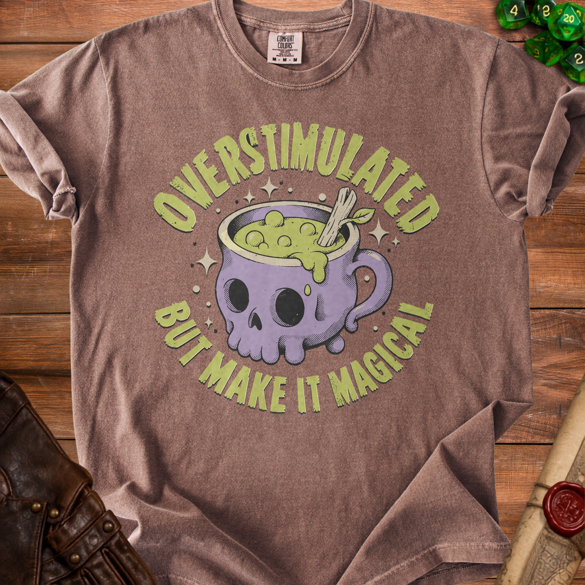 Brown t-shirt with skull cauldron graphic and text "Overstimulated But Make It Magical."