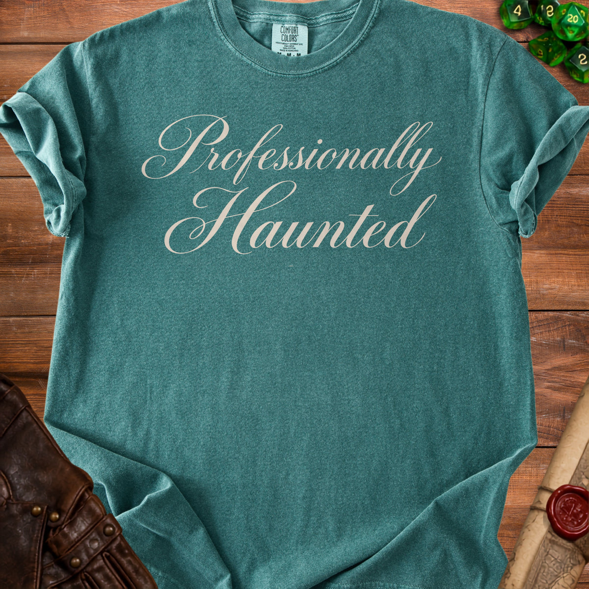Teal t-shirt with "Professionally Haunted" text in cream cursive script.