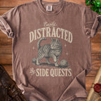 Brown t-shirt with a graphic of a cat and dice, text reads "Easily Distracted By Side Quests".