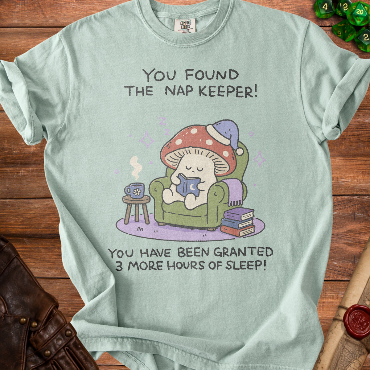 T-shirt with illustration of a mushroom person reading, wearing a sleep cap. Text: "You found the nap keeper! You have been granted 3 more hours of sleep!"