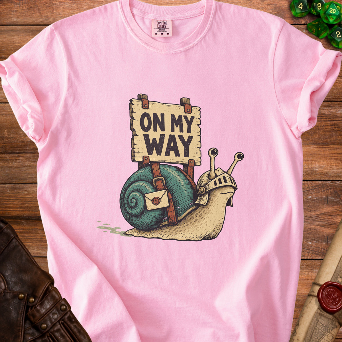 Pink t-shirt with cartoon snail wearing armor and holding sign that says "ON MY WAY".