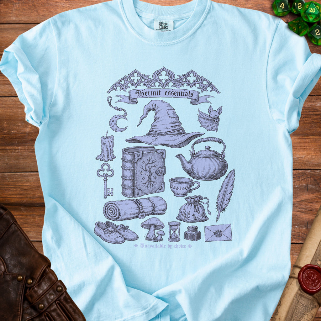 Light blue t-shirt with "Hermit essentials" text and gothic illustrations of witchy items.