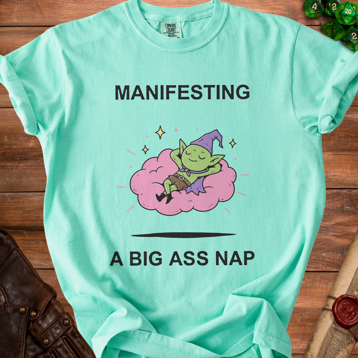 Mint t-shirt with "MANIFESTING A BIG ASS NAP" and a sleeping goblin on a cloud.