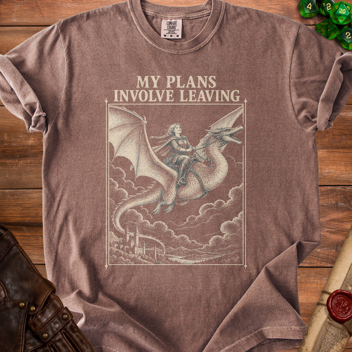 Brown t-shirt featuring a graphic of a person riding a dragon above clouds and castles, with the text MY PLANS INVOLVE LEAVING.