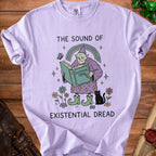 Light purple t-shirt with graphic of wizard reading "Existential Tome" under rainbow.