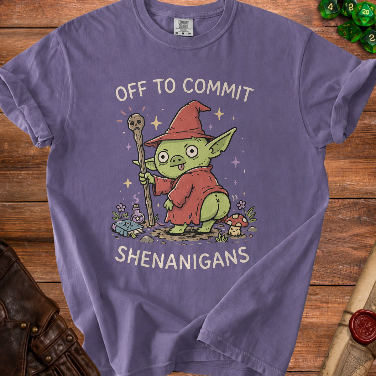 Purple t-shirt with illustration of a goblin wizard holding a staff and text "OFF TO COMMIT SHENANIGANS".