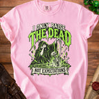 Pink t-shirt with grim reaper and skeleton graphic reading "I Only Raise the Dead Not Expectations."