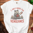 White t-shirt with an opossum holding a chainsaw, flanked by skulls and candles, text reads "I ONLY WAKE FOR VENGEANCE".
