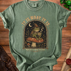 Green t-shirt with a frog wearing a witch hat holding coffee and text "IT IS WHAT IT IS And it's pretty terrible".