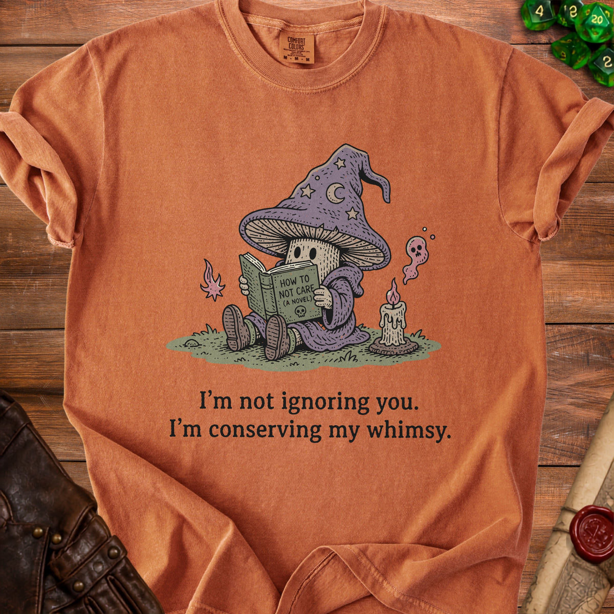 T-shirt with mushroom wizard reading "How to Not Care (A Novel)" and text "I'm not ignoring you. I'm conserving my whimsy."