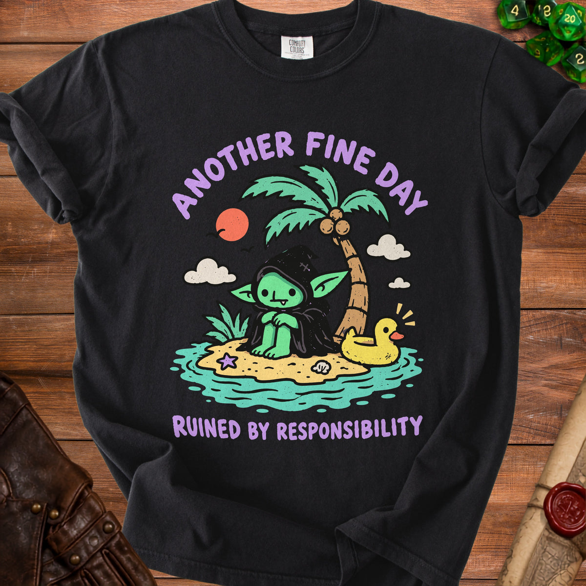 Black t-shirt with green goblin on island, palm tree, rubber duck, and text "Another Fine Day Ruined by Responsibility".