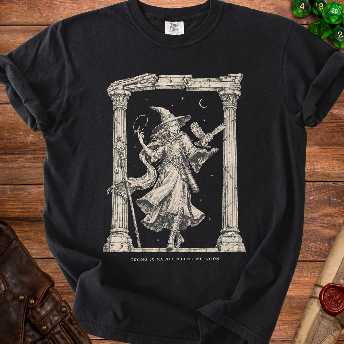 Black t-shirt with a sketch of a witch holding a staff, an owl, and a book.