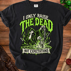 Black t-shirt with green graphic of Grim Reaper holding skeleton, text "I ONLY RAISE THE DEAD NOT EXPECTATIONS".