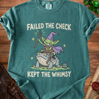 Green t-shirt with a goblin riding a toad, saying "FAILED THE CHECK KEPT THE WHIMSY."