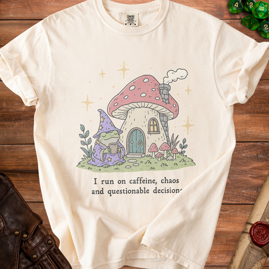 Cream t-shirt with frog wizard and mushroom house graphic, reads "I run on caffeine, chaos and questionable decision."