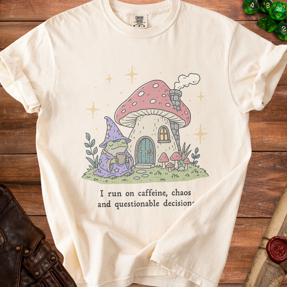 Cream t-shirt with frog wizard and mushroom house graphic, reads "I run on caffeine, chaos and questionable decision."