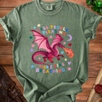 Green t-shirt with a pink dragon breathing fire and text "less people pleasing more fire breathing".