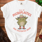 White t-shirt with a cartoon creature wearing a cowboy hat and boots, text reads "Full of Microplastics and Existential Dread."