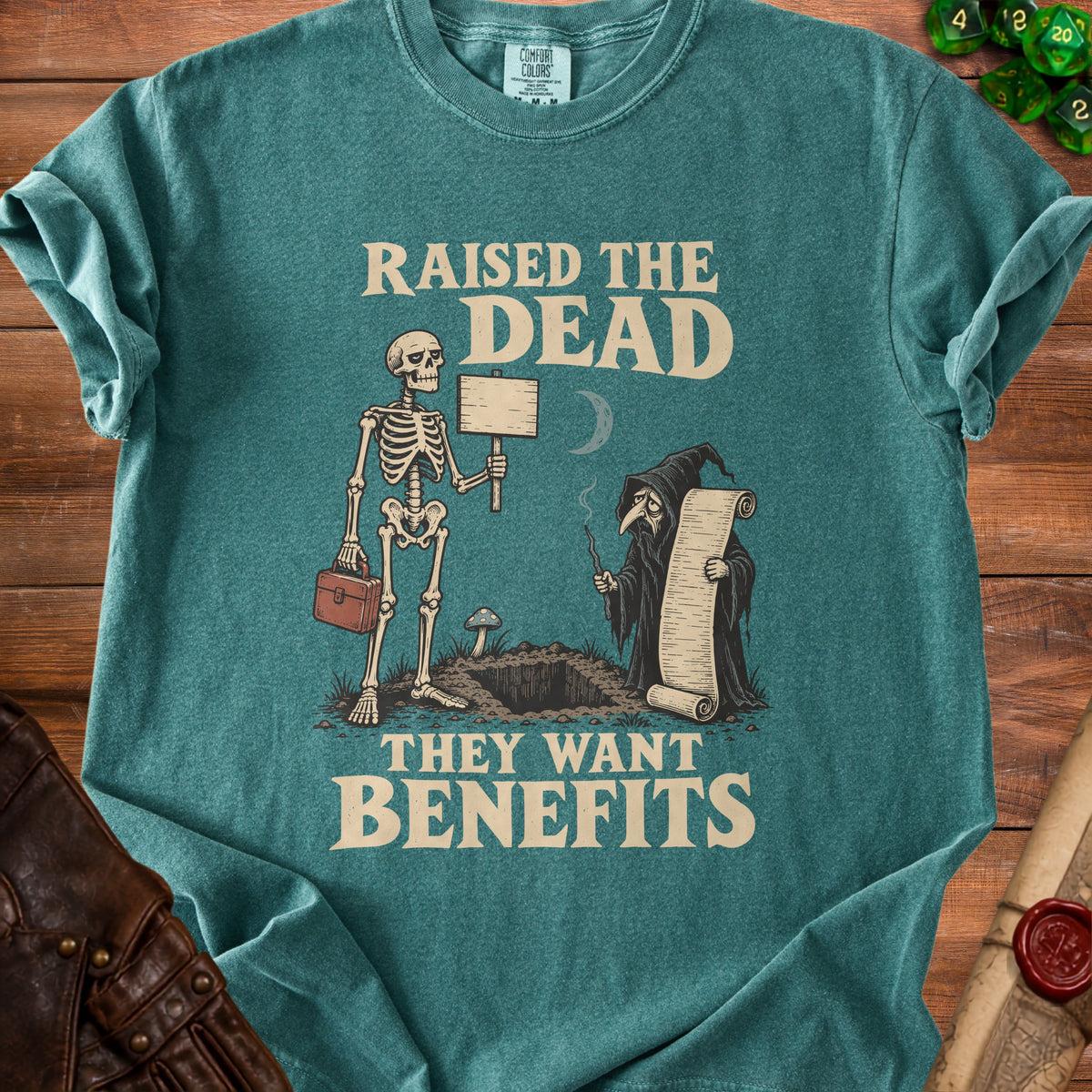 Green t-shirt with skeleton and grim reaper graphic reading "Raised the Dead, They Want Benefits."