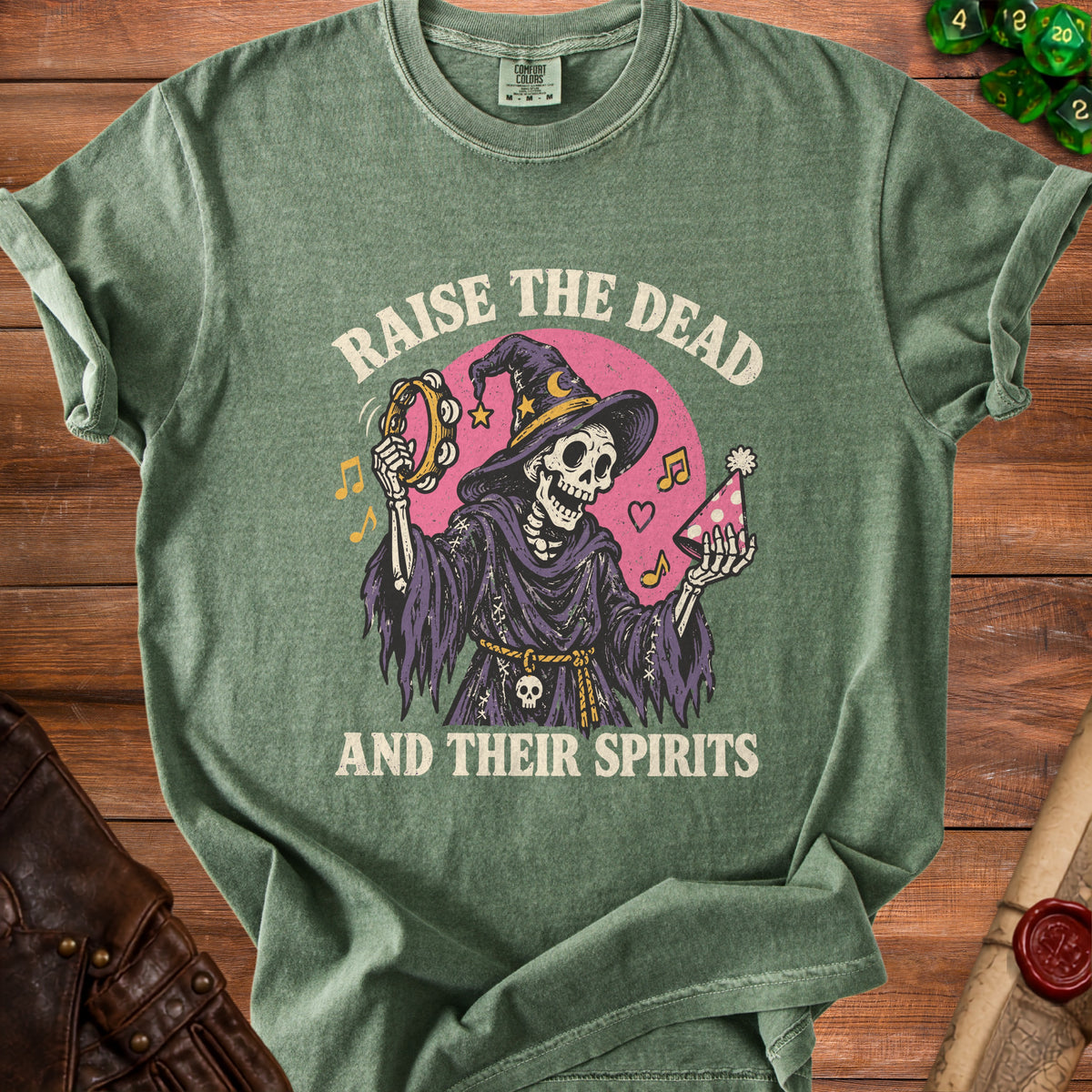 Green t-shirt with a skeleton in a witch hat playing a tambourine and holding a party hat.