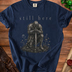 Navy t-shirt with "still here" text and knight in armor illustration.