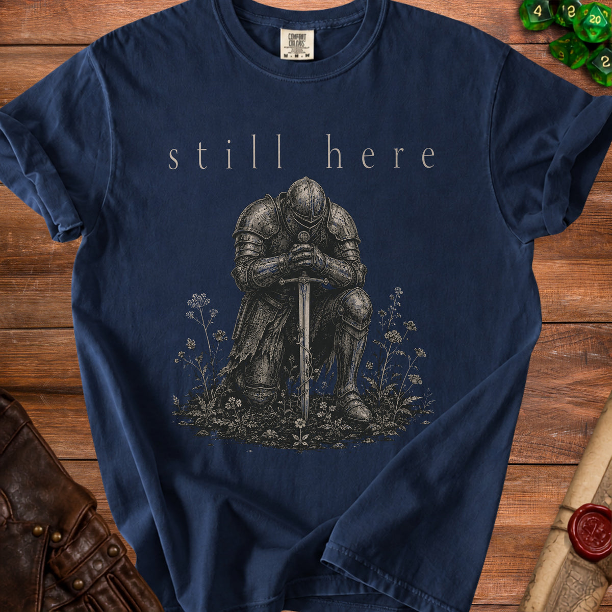 Navy t-shirt with "still here" text and knight in armor illustration.
