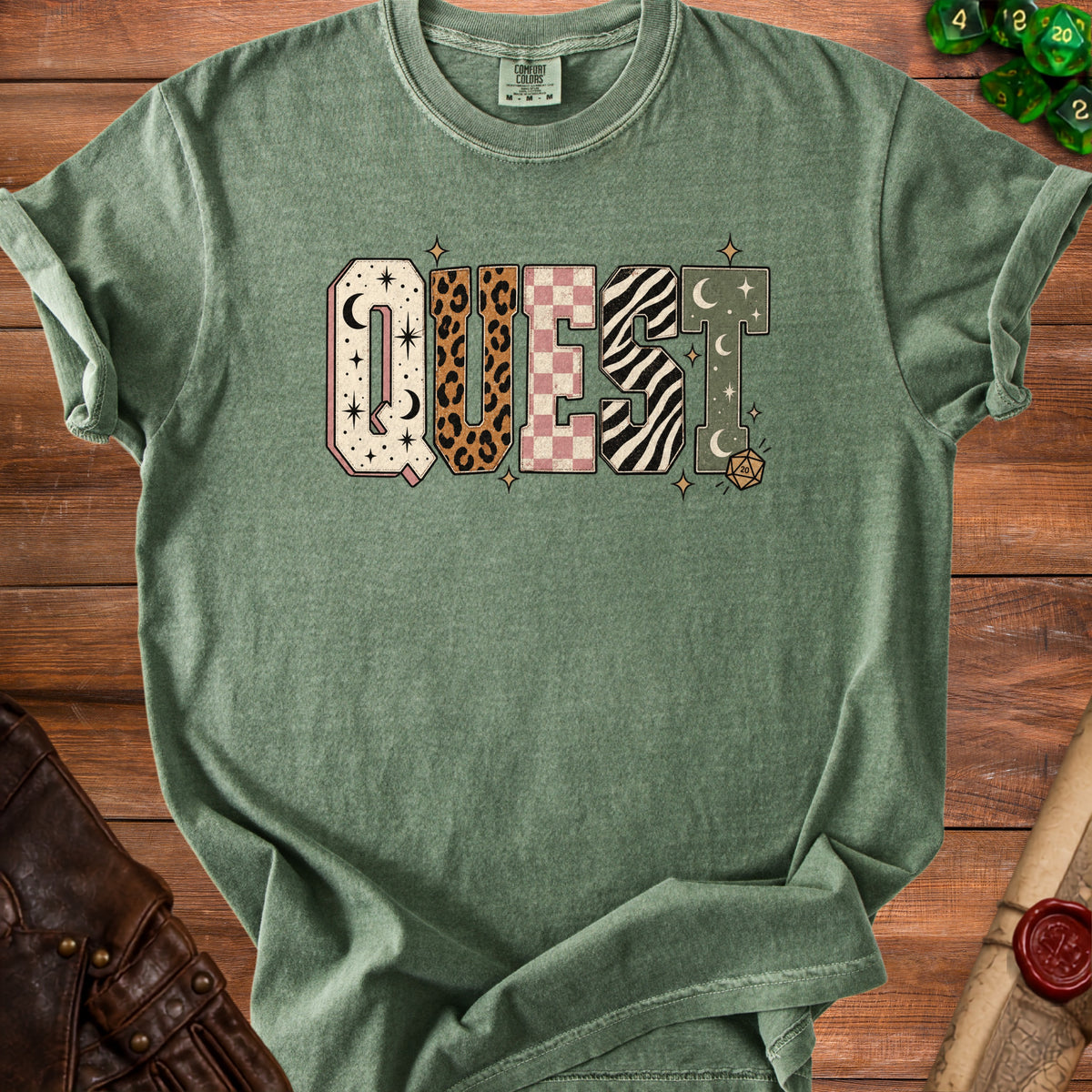 Green t-shirt with "QUEST" graphic featuring animal prints and celestial patterns.