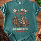 T-shirt with cartoon cats and dogs in medieval armor fighting, text "Not a phone in sight, Just people living in the moment."
