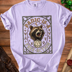 Purple t-shirt with a raccoon and dice graphic that reads "Panic is a Free Action".