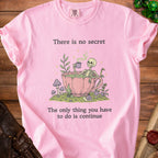 Pink t-shirt with skeleton in teacup graphic and text: "There is no secret. The only thing you have to do is continue."
