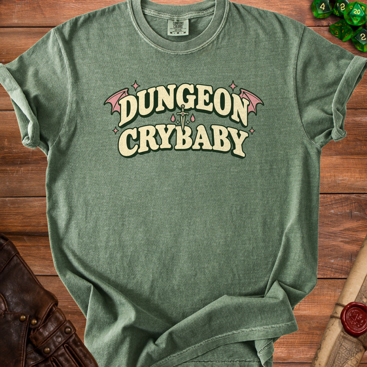 Green t-shirt with "Dungeon Crybaby" text, a sword, and pink bat wings.
