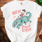 White t-shirt with skeleton riding dragon, text "NOT MY FIRST CURSE".