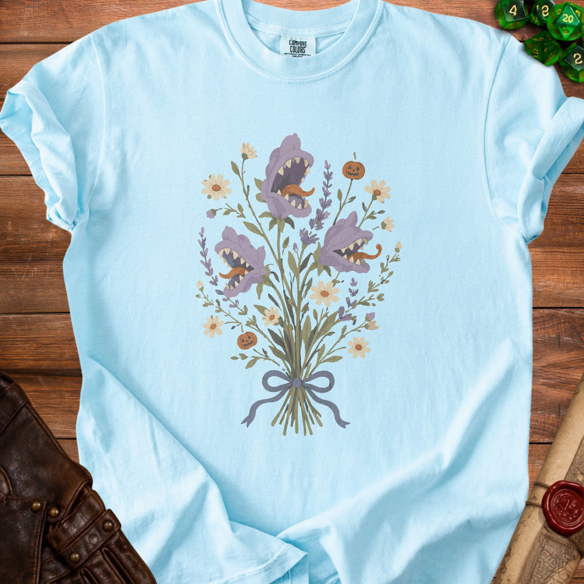 Light blue t-shirt with a graphic of carnivorous plants and pumpkins, tied with a ribbon.