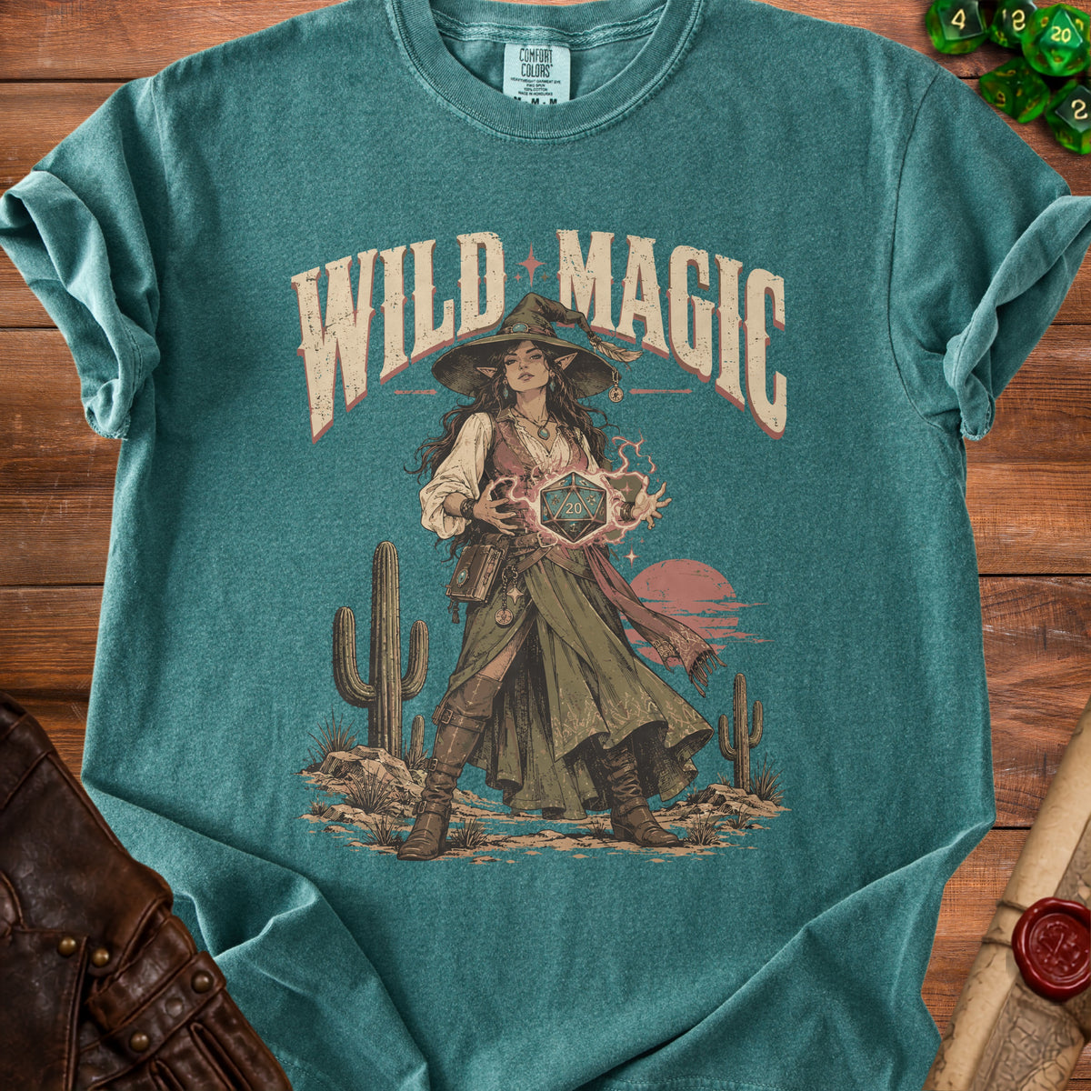 T-shirt graphic of a witch holding a d20 die with "WILD MAGIC" text.