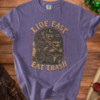 Purple t-shirt with goblins in a cart, text "LIVE FAST EAT TRASH".