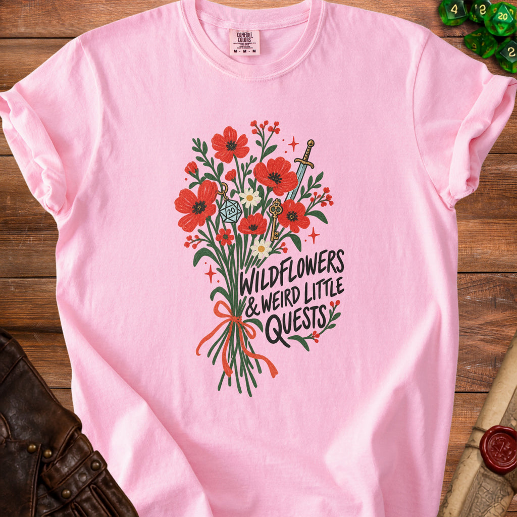 Pink t-shirt with wildflowers, sword, keys, and "Wildflowers & Weird Little Quests" text.
