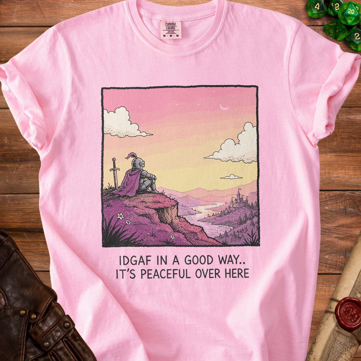 Pink t-shirt with graphic of knight overlooking a castle and text "IDGAF IN A GOOD WAY.. IT'S PEACEFUL OVER HERE."