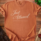 Orange t-shirt with "Just Attuned" and "emotionally attached to questionable artifacts" text.
