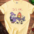 Yellow t-shirt with cartoon wizard, cat, and laptop on fire, reading "It's OK."