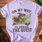 Purple t-shirt with a frog wizard holding a sword, text "On My Way To Derail The Quest."