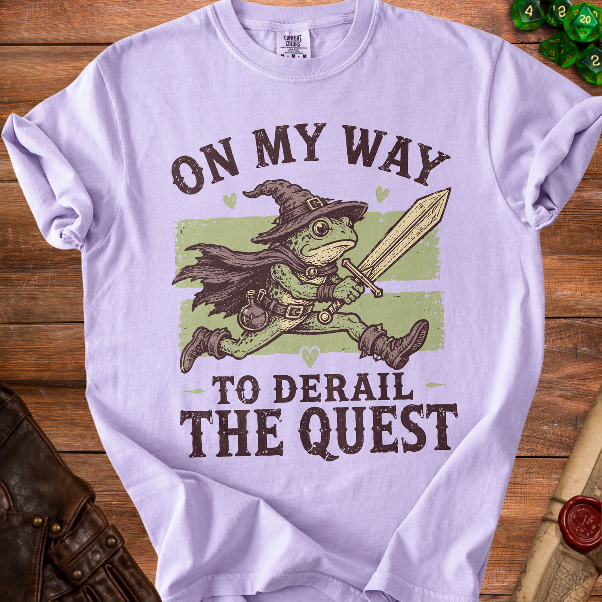 Purple t-shirt with a frog wizard holding a sword, text "On My Way To Derail The Quest."