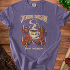 Purple t-shirt with "Coven Before Conversation First We Brew" text and graphic.