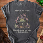 Dark gray t-shirt with a witch frog in a cauldron, with text "There is no secret".
