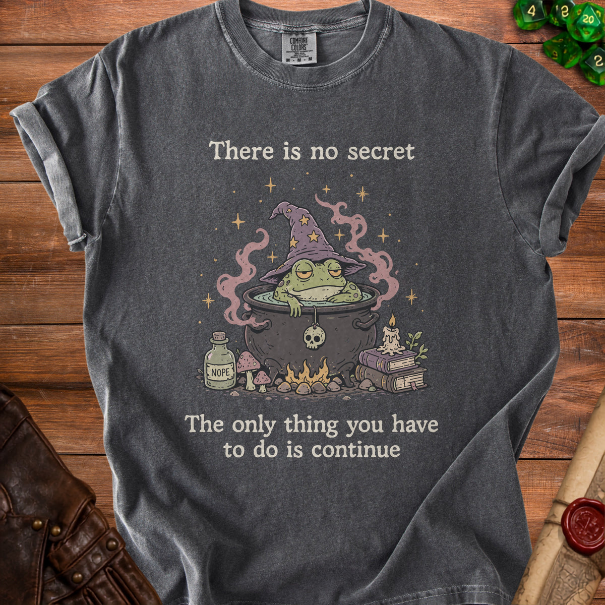 Dark gray t-shirt with a witch frog in a cauldron, with text "There is no secret".