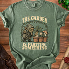 Green t-shirt with "The Garden Is Plotting Something" text and a goblin watering plants.